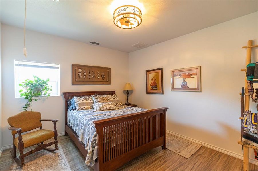 Room featuring wood-finish flooring and a rectangular window with blinds Room featuring wood-finish flooring and a rectangular window with blinds