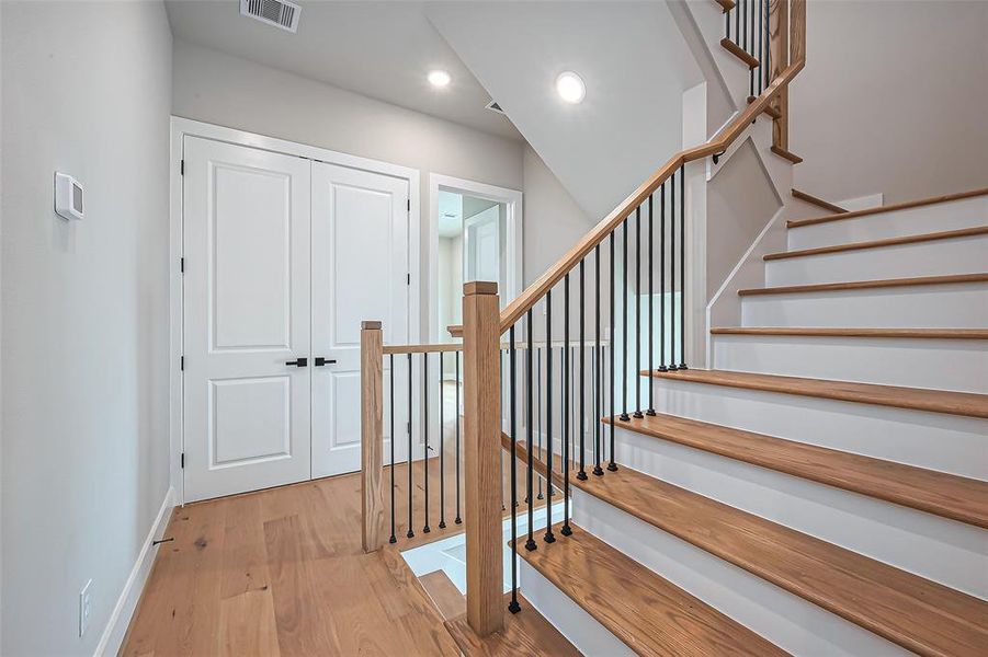 Bright and modern entryway featuring a staircase with wooden steps and sleek black iron balusters. The double doors and neutral walls enhance the welcoming, contemporary ambiance.