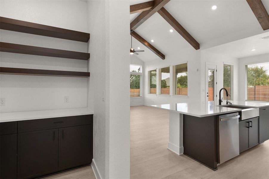 Kitchen with light wood-style flooring, dishwasher, an island with sink, recessed lighting, and open shelves