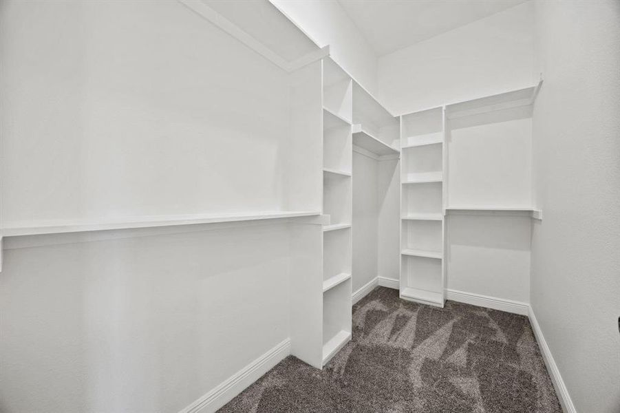 Walk-in closet featuring built-in shelving, clothing rods, baseboard trim, and textured wall finish Walk-in closet featuring built-in shelving, clothing rods, baseboard trim, and textured wall finish