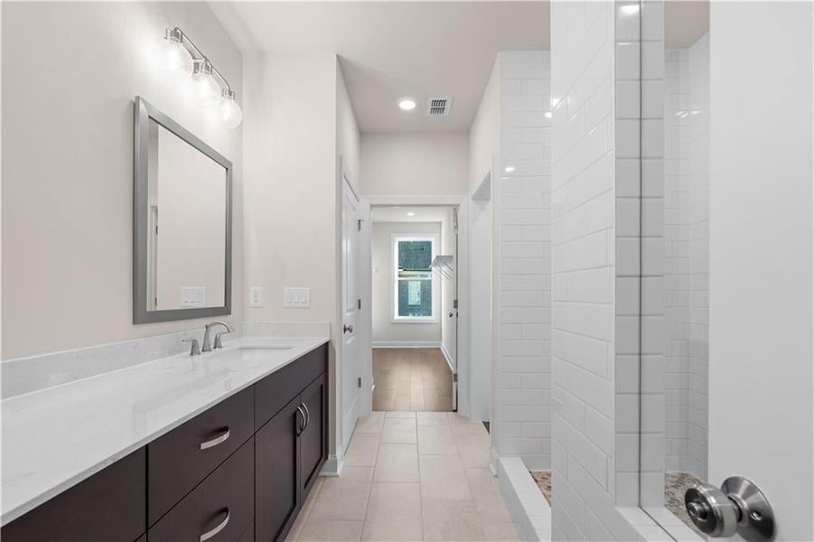 Bathroom with vanity, tiled shower, recessed lighting, and light tile patterned flooring