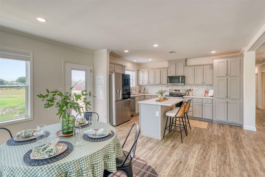 A contemporary kitchen and dining space with rich wood-look flooring and a bright outlook. A contemporary kitchen and dining space with rich wood-look flooring and a bright outlook.