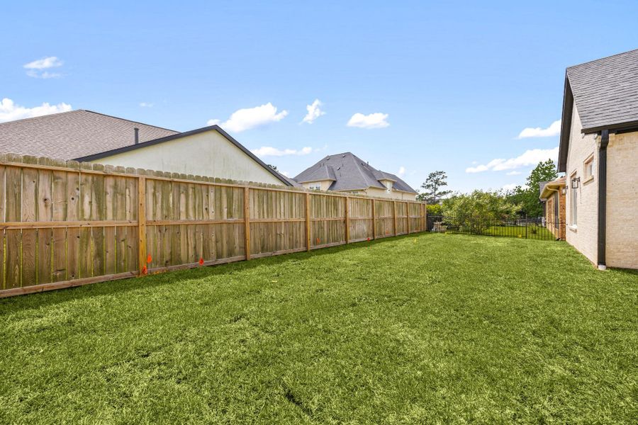 Spacious, fenced backyard with lush grass, perfect for outdoor activities and privacy.