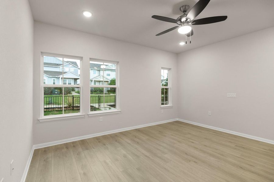 This room features light-colored flooring, neutral walls, and a ceiling fan with an integrated light fixture
