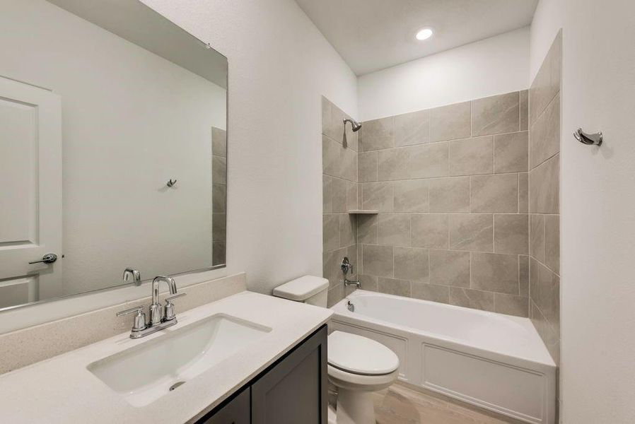 Full bathroom featuring tiled shower / bath combo, vanity, and toilet