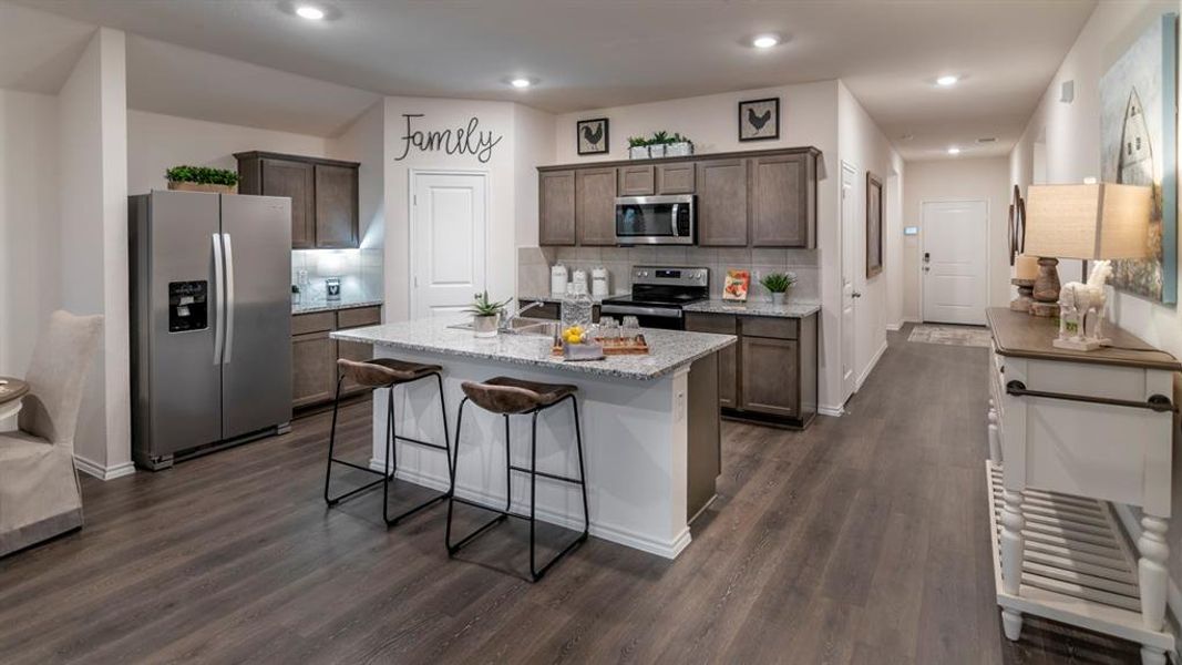 Kitchen featuring stainless steel appliances, dark wood finish cabinets, decorative backsplash, a center island with sink, and recessed lighting