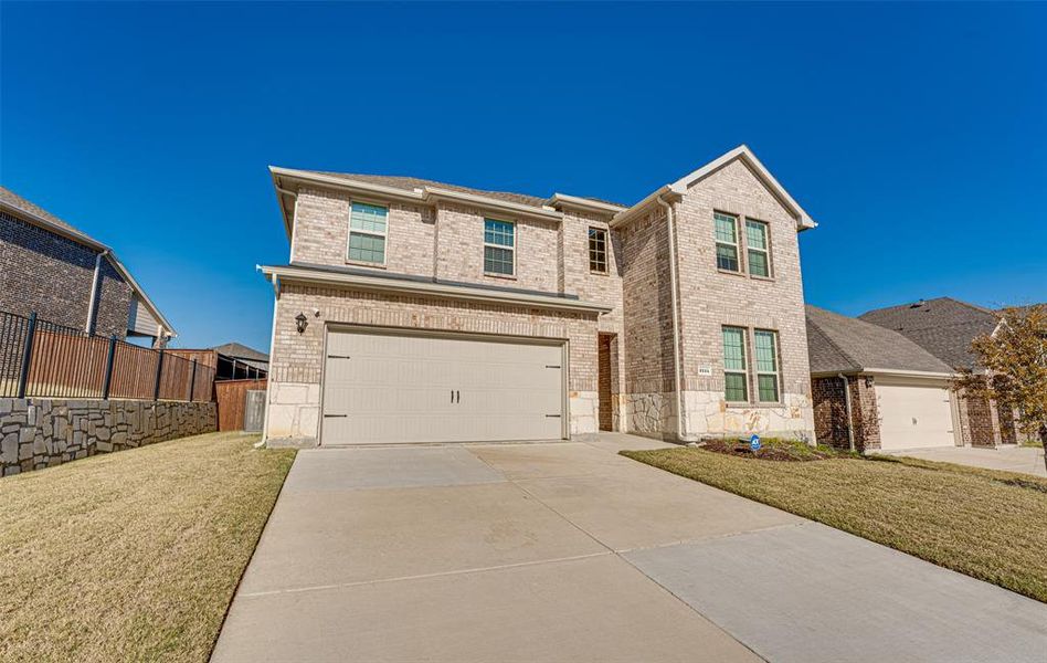 View of front facade with driveway, brick siding, and a garage