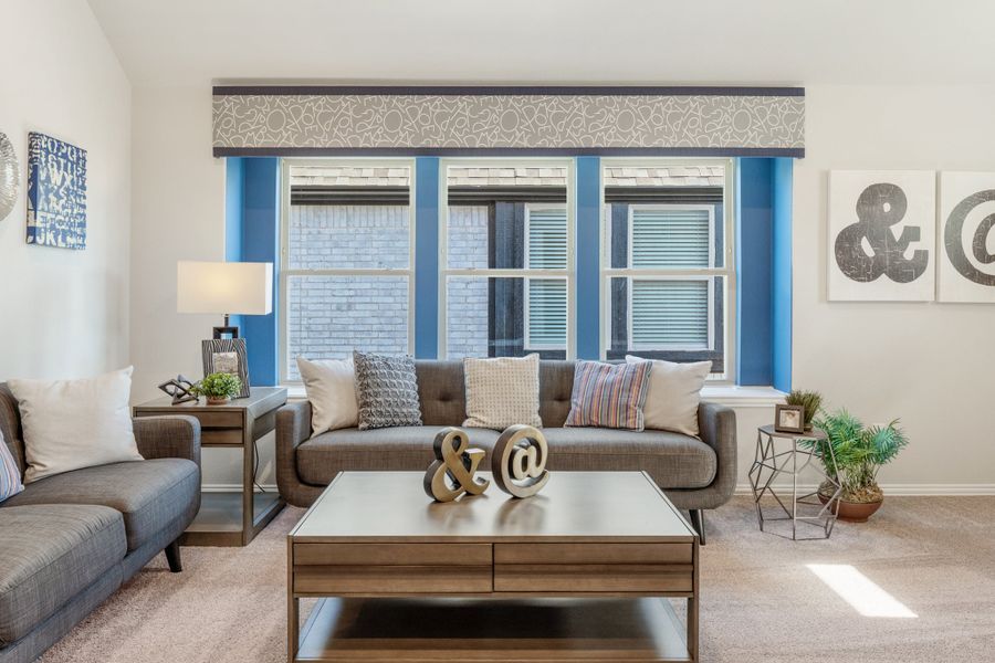 Living room with gray sofa, wood coffee table, and large blue-trimmed triple window with decorative valance