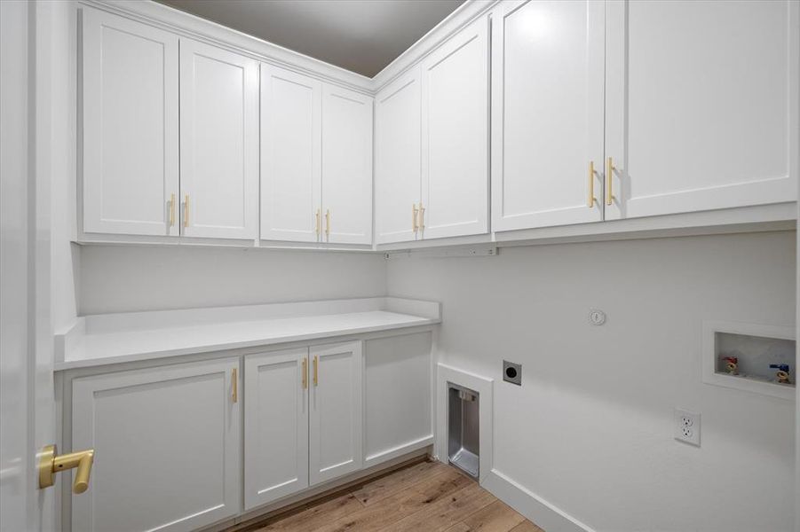 Laundry room featuring light wood finished floors, hookup for a washing machine, electric dryer hookup, and cabinet space