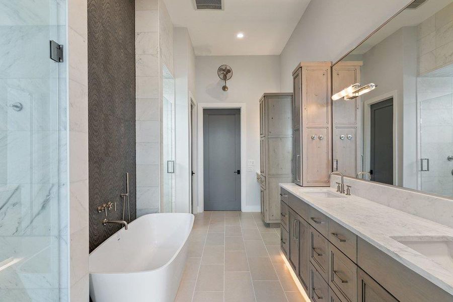 Spacious bathroom featuring a freestanding tub, expansive vanity with dual undermount sinks, stone countertop, and wood-finish cabinetry