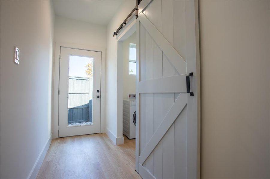 Doorway featuring a barn door, washer / clothes dryer, and light hardwood / wood-style flooring