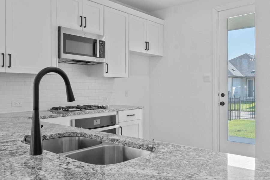 Kitchen with white cabinets, light stone counters, stainless steel appliances, and decorative backsplash Kitchen with white cabinets, light stone counters, stainless steel appliances, and decorative backsplash
