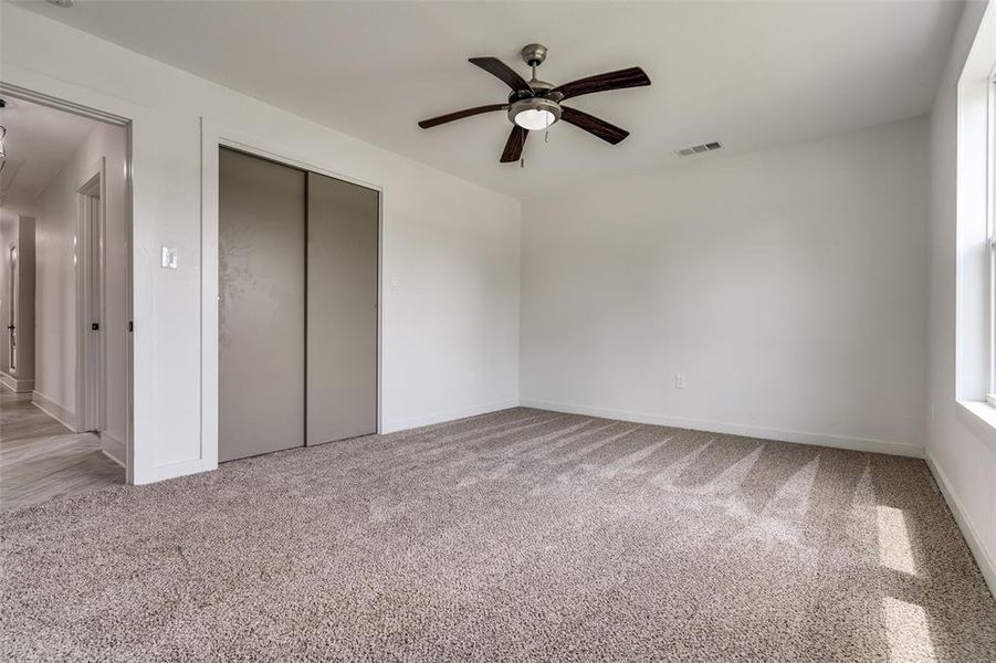 One of the secondary bedrooms featuring upgraded ceiling fan package , custom closets, brand new windows and a large sized room for the little ones.