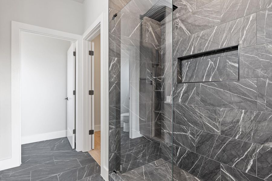 Full bath with a marble finish shower and dark marble finish floors