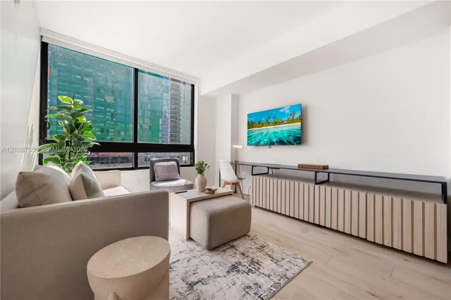 Floor-to-ceiling windows, wood-finish flooring, and built-in fluted cabinetry with a metal-frame desktop surface Floor-to-ceiling windows, wood-finish flooring, and built-in fluted cabinetry with a metal-frame desktop surface