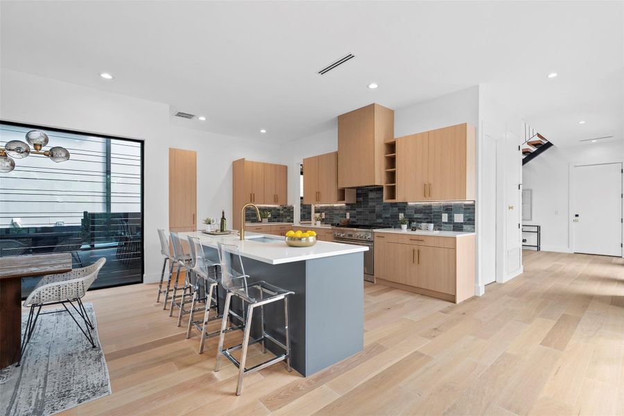 The kitchen features wood cabinetry, a dark tiled backsplash, and a central island with a light-colored countertop