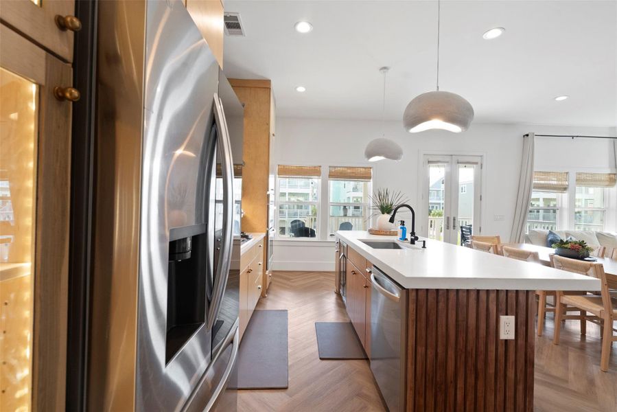 A seamless view of the kitchen highlights the functional flow between the stainless steel refrigerator and the central island. Clean lines, light wood cabinetry, and neutral finishes reflect a modern coastal aesthetic—balancing simplicity with warmth. A seamless view of the kitchen highlights the functional flow between the stainless steel refrigerator and the central island. Clean lines, light wood cabinetry, and neutral finishes reflect a modern coastal aesthetic—balancing simplicity with warmth.