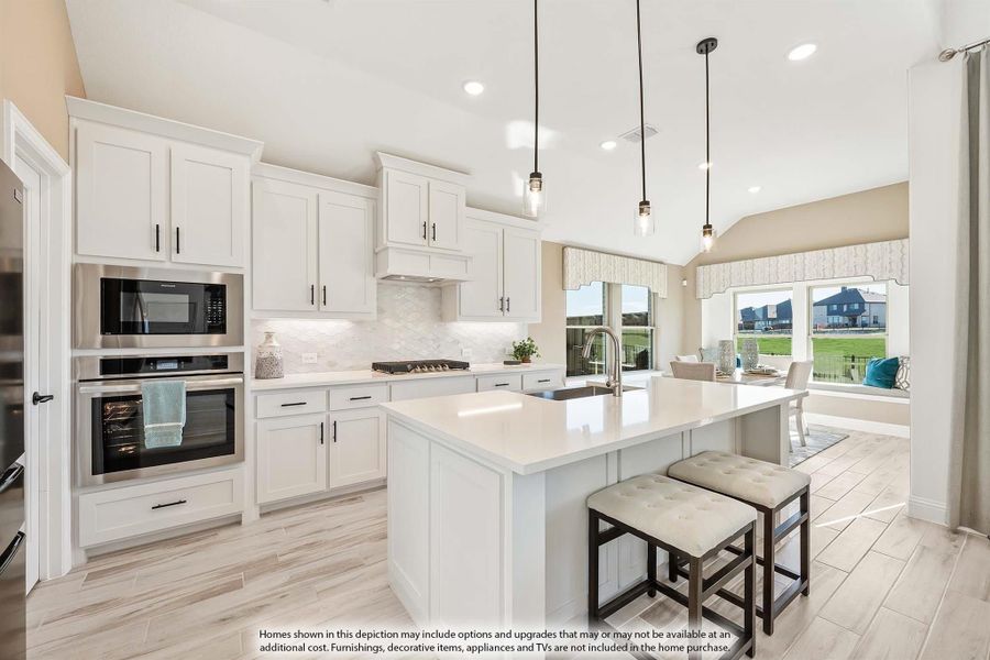 Kitchen with white cabinets, large island with seating, stainless steel appliances, and pendant lights over light wood floors Kitchen with white cabinets, large island with seating, stainless steel appliances, and pendant lights over light wood floors