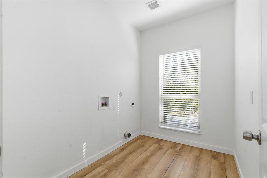 Laundry area featuring hookup for a gas dryer, washer hookup, wood finished floors, and hookup for an electric dryer Laundry area featuring hookup for a gas dryer, washer hookup, wood finished floors, and hookup for an electric dryer