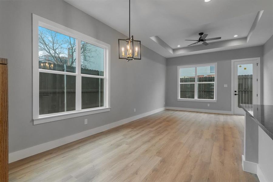 Unfurnished dining area featuring a tray ceiling, recessed lighting, light wood-style floors, and baseboards