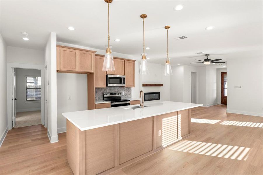 Kitchen featuring pendant lighting, appliances with stainless steel finishes, light wood finished floors, tasteful backsplash, and ceiling fan