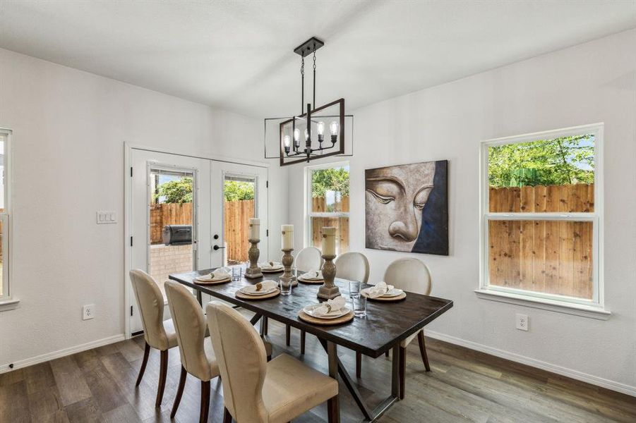 Dining area featuring a notable chandelier, french doors, plenty of natural light, and dark wood-type flooring