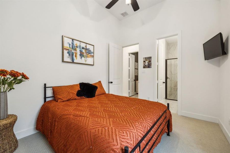 Bedroom featuring light carpet, baseboards, ensuite bathroom, and ceiling fan