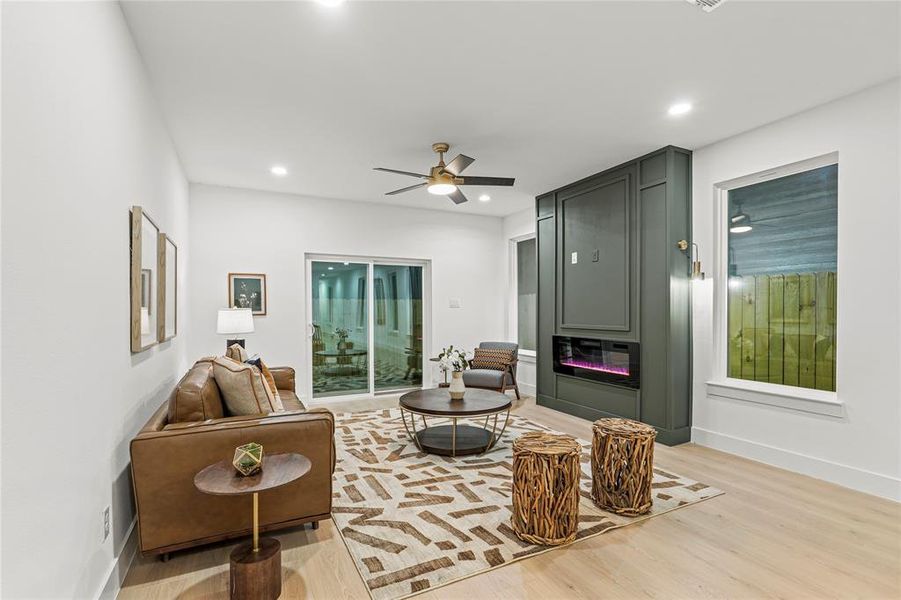 Living area with light wood-style flooring, ceiling fan, a fireplace, and recessed lighting