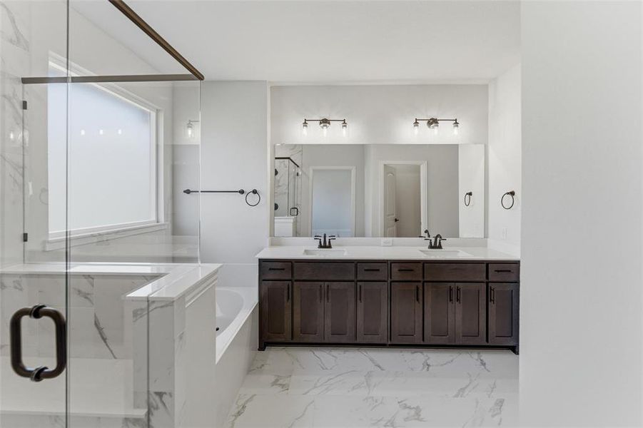 Bathroom with a marble finish shower, double vanity, a garden tub, and light marble finish floors