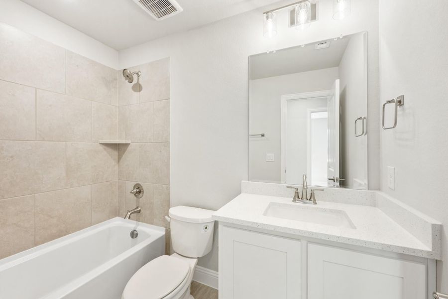 Bathroom with tiled tub-shower combo, white vanity with quartz countertop, and large mirror Bathroom with tiled tub-shower combo, white vanity with quartz countertop, and large mirror