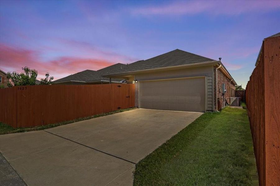 Property exterior at dusk featuring driveway, a garage, and brick siding Property exterior at dusk featuring driveway, a garage, and brick siding