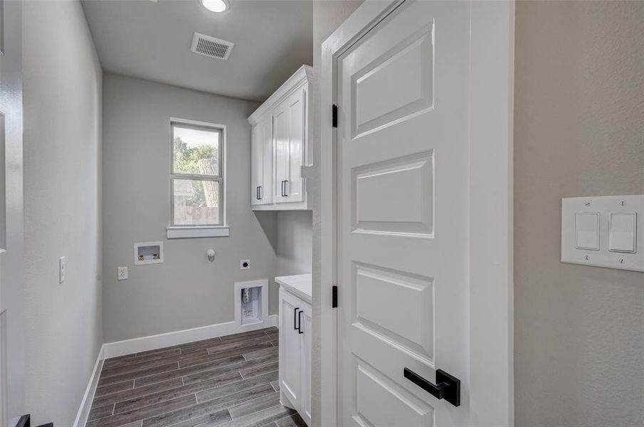 Laundry room featuring, cabinet space, wood look tiled floors, washer dryer hookups,