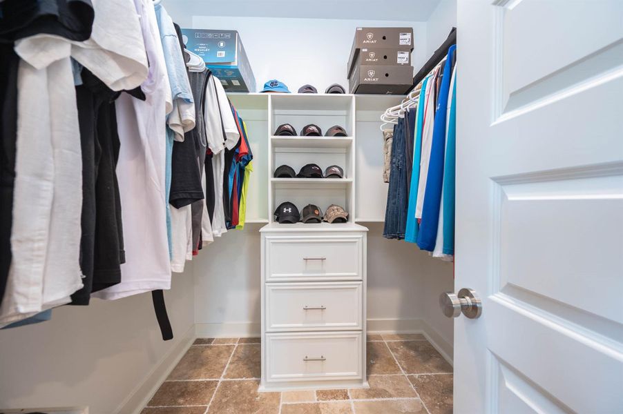 The spacious walk-in primary closet offers ample hanging space, built-in shelving, and additional storage drawers to keep everything organized. Bright finishes and a functional layout make this space both practical and inviting.