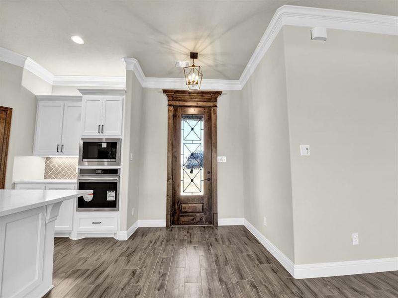 Foyer featuring ornamental molding, a notable chandelier, and light hardwood / wood-style floors