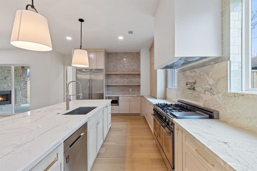 The kitchen is a true chef’s dream, featuring stunning quartzite countertops, a custom plaster vent hood, white oak custom cabinets, and Bertazzoni 48-inch range and refrigerator columns, offering both beauty and practicality.