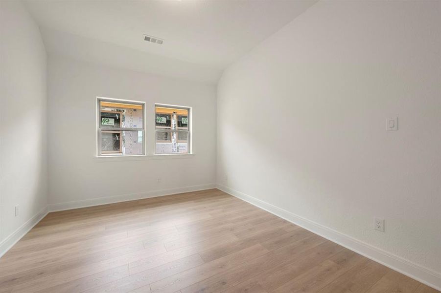 Unfurnished room with vaulted ceiling and light wood-type flooring Unfurnished room with vaulted ceiling and light wood-type flooring