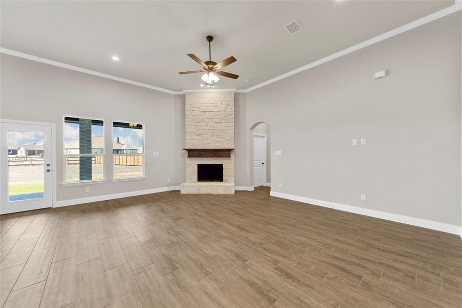 Unfurnished living room featuring ceiling fan, crown molding, a fireplace, and hardwood / wood-style floors