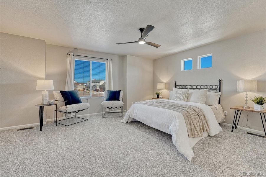 Primary suite with carpet, ceiling fan...