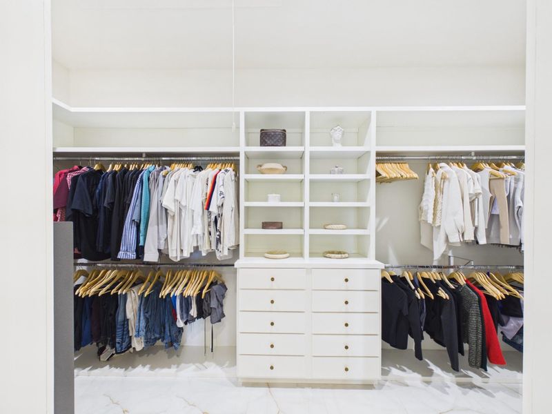 Spacious walk in closet with built in shelving, drawers, and ample hanging space