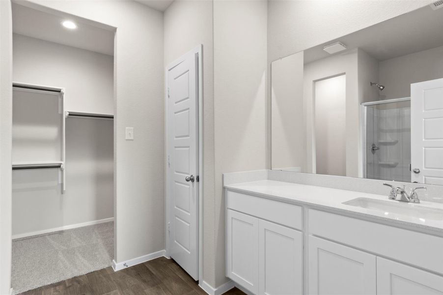 Full bath featuring a shower with door, wood finished floors, and vanity Full bath featuring a shower with door, wood finished floors, and vanity