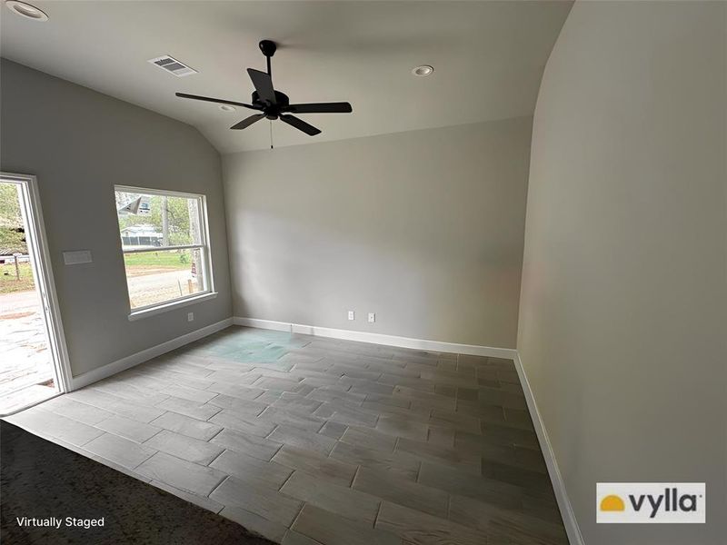 The spacious living room area features high-quality tile flooring and is equipped with a ceiling fan with lights.