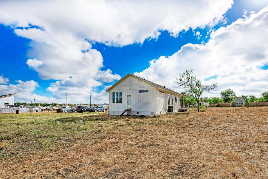 Board and batten siding defines this single-level home set on a grassy acreage under expansive skies.