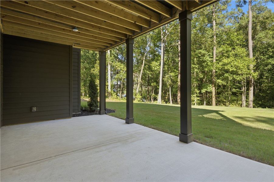 A covered concrete patio overlooks a grassy backya