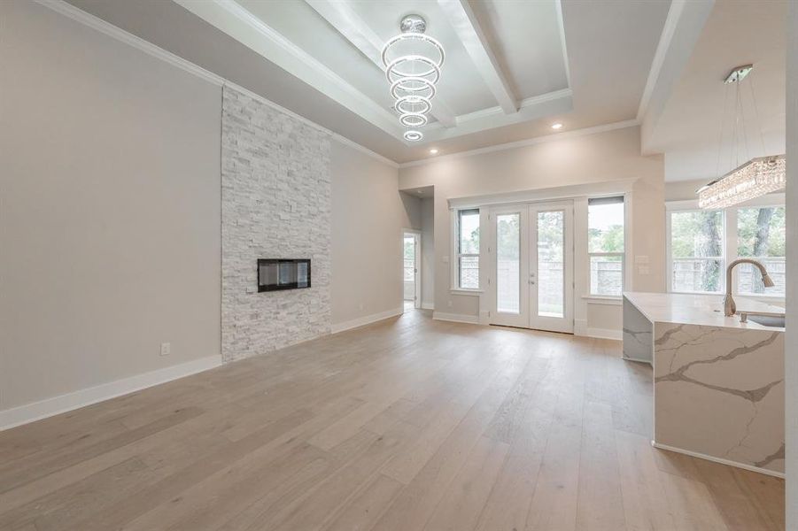 Living area with a chandelier, french doors, light wood-style flooring, ornamental molding, and beam ceiling