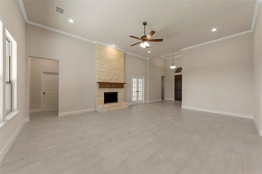 Unfurnished living room with a fireplace, ceiling fan, and crown molding