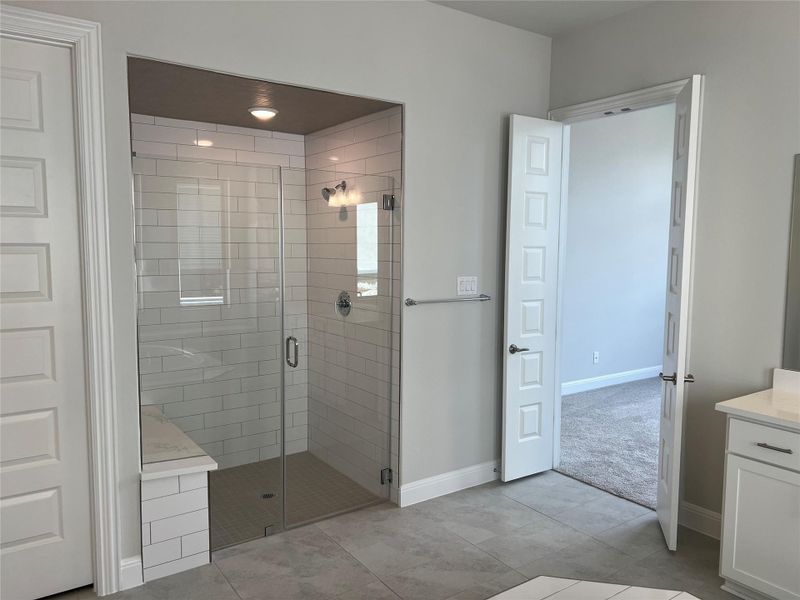 Full bath with a shower stall, vanity, and tile patterned floors