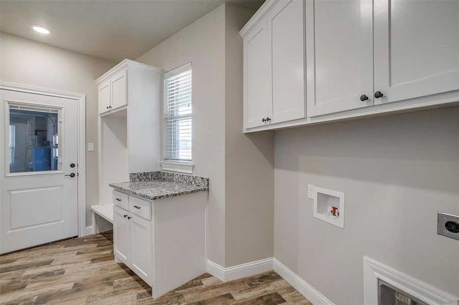 Washroom with electric dryer hookup, washer hookup, sink and cabinets