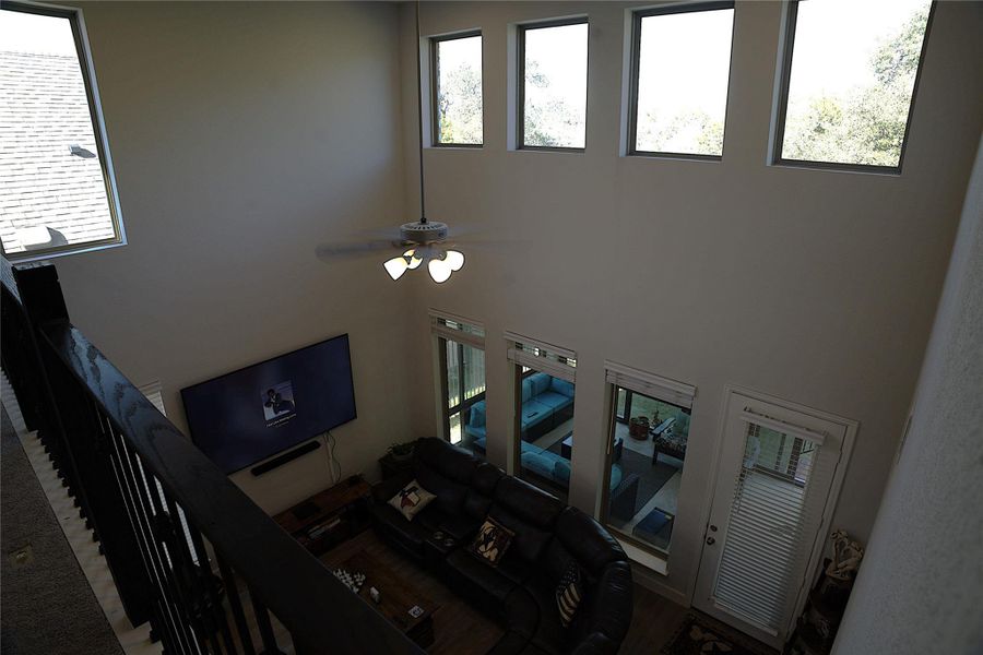 Living area featuring ceiling fan, a high ceiling, and wood finished floors Living area featuring ceiling fan, a high ceiling, and wood finished floors