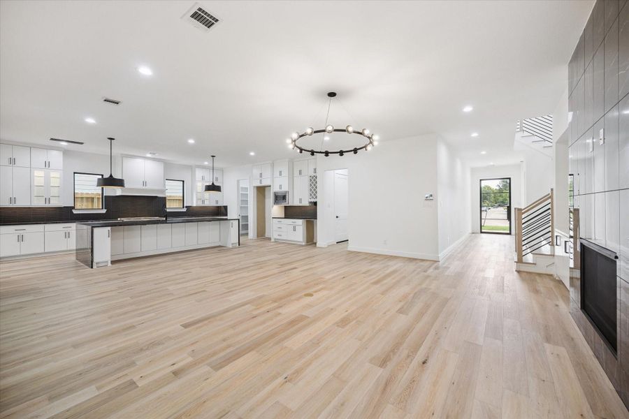 An expansive open-concept layout seamlessly connects the living area, dining space, and chef’s kitchen. Oversized windows and sleek lighting fixtures create a bright, inviting atmosphere, while the modern fireplace adds warmth and style to the design. An expansive open-concept layout seamlessly connects the living area, dining space, and chef’s kitchen. Oversized windows and sleek lighting fixtures create a bright, inviting atmosphere, while the modern fireplace adds warmth and style to the design.