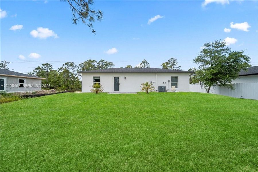Expansive backyard featuring a manicured lawn, stucco exterior, and a privacy fence Expansive backyard featuring a manicured lawn, stucco exterior, and a privacy fence